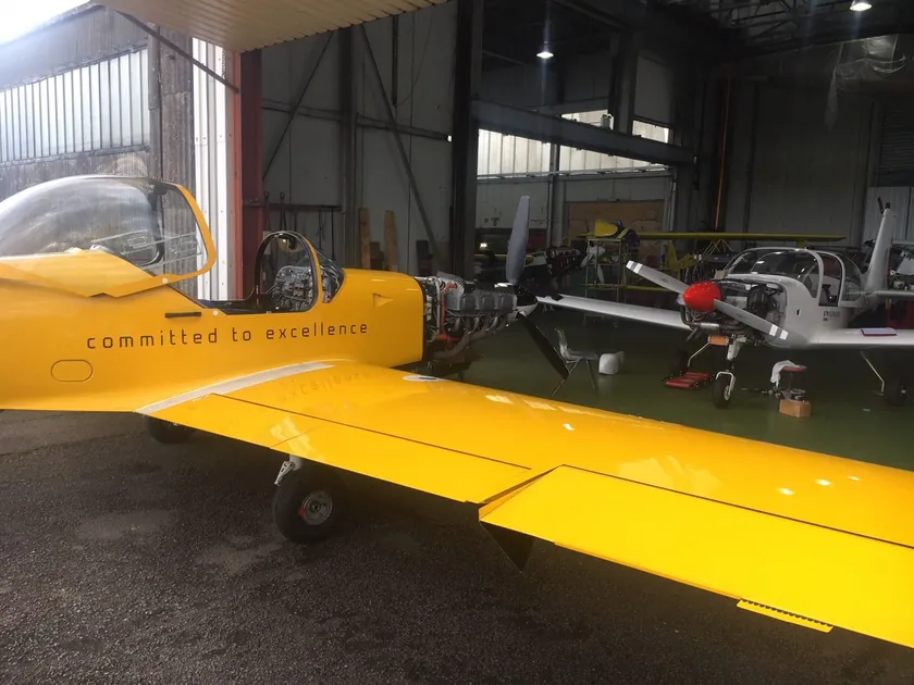 Yellow Slingsby training aircraft parked inside the hangar