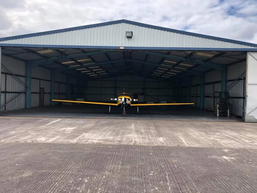 Light aircraft at the far end of an open hangar