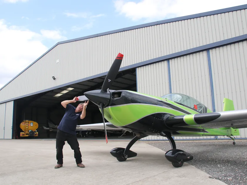 Engineer moving a green and black light aircraft outside the hangar