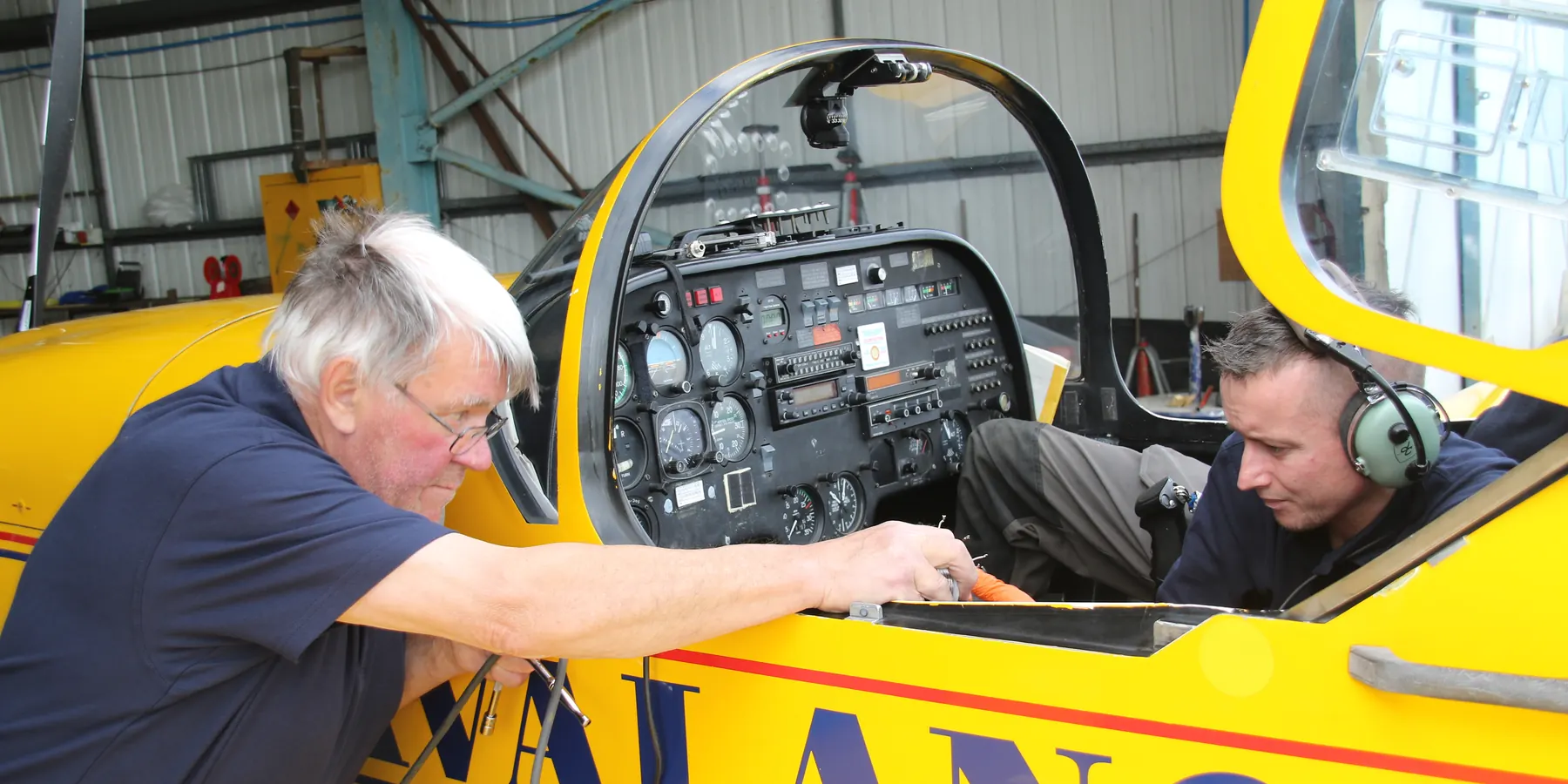 Two Swift Aero engineers working in the cockpit of a yellow Slingsby aircraft