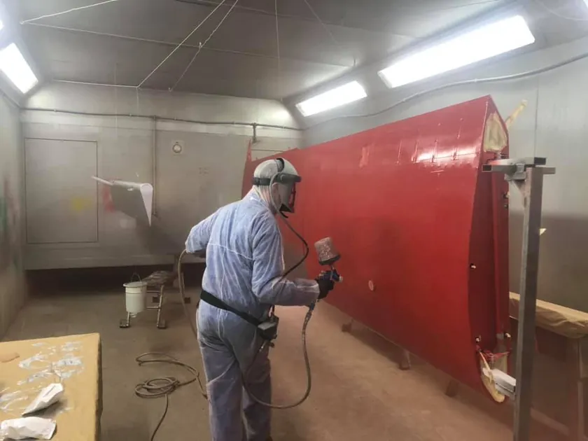 Aircraft panel being spray painted in a paint booth