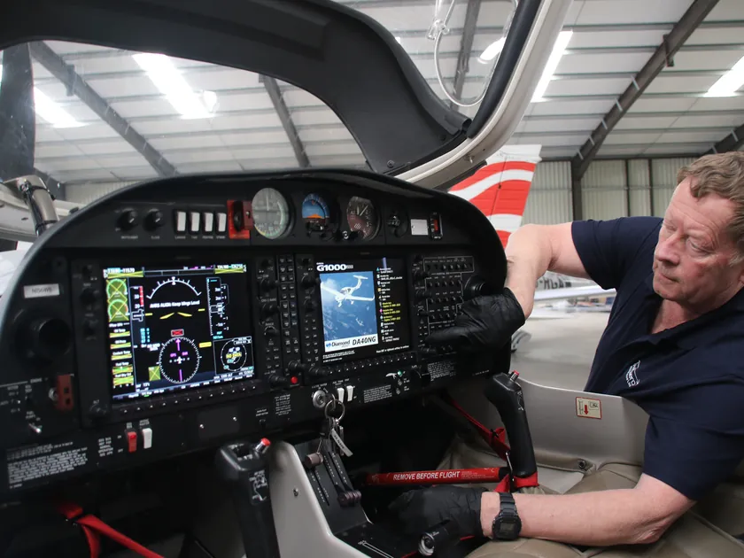 Swift Aero engineer reaching into the cockpit of a light aircraft to work on its glass instrument panel in the hangar