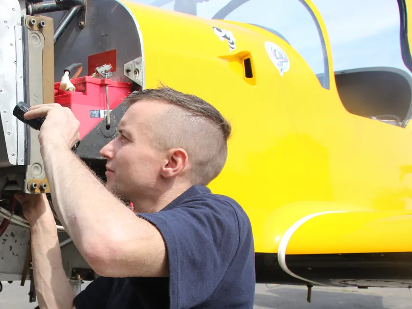 Engineer inspecting the airframe skin of a yellow aircraft