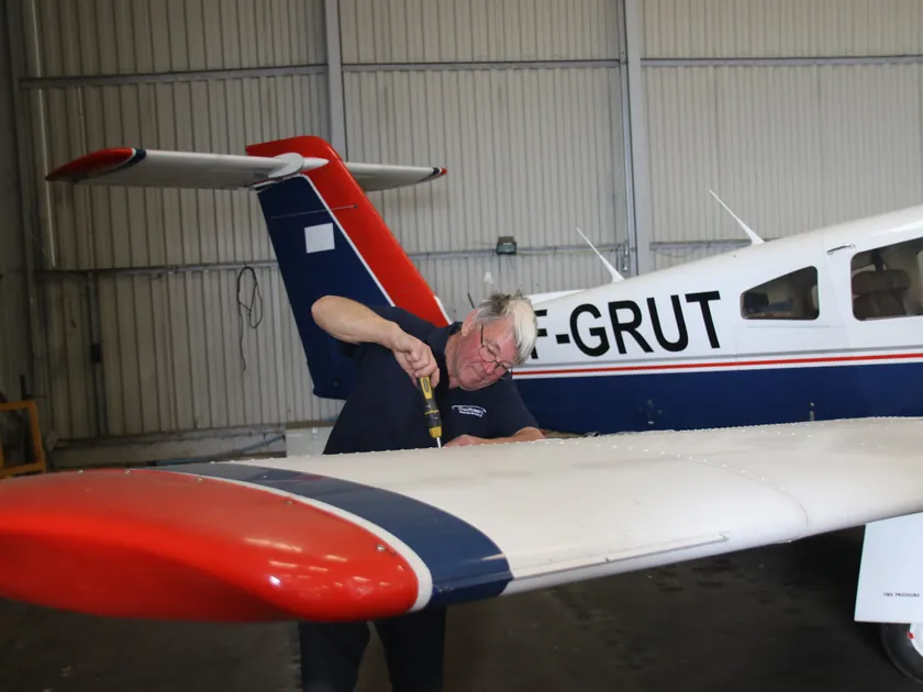 Engineer working on the tail of a Piper aircraft